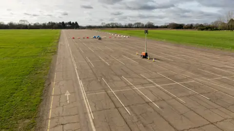 Bovingdon Airfield Studios An empty runway at Bovingdon Airfield which is part of the studio. Some lighting and safety equipment has been set up on the runway.