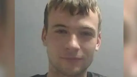 A police custody picture of Garforth who has short brown hair and is wearing a dark coloured t-shirt