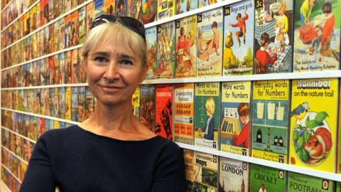 Helen Day standing in front of a large collection of Ladybird books