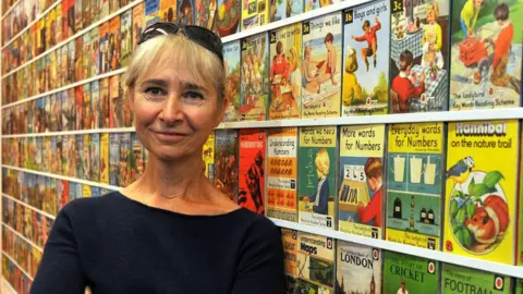 Ladybirdflyawayhome Helen Day standing in front of a large collection of Ladybird books