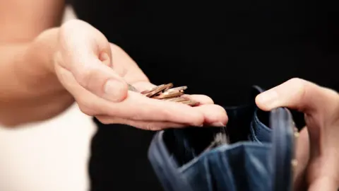 Getty Images A woman's hand holding loose change