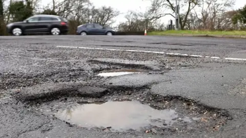 PA Media Large pothole in foreground