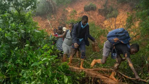 Getty Images Children walking through mud as they are rescued