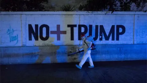 EPA A man walks past graffiti reading No more Trump