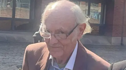 BBC Keith Edwards outside Nottingham Magistrates' Court wearing a suit and glasses