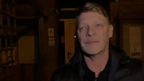 Paul MacGregor in front of the village hall at night