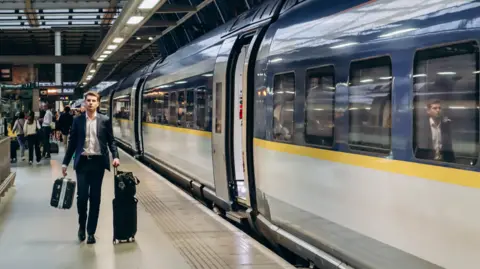 Getty Images Man in suit drags suitcase alongside Eurostar train