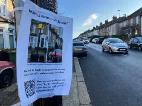 Sign on lampost reads 'in loving memory of speedy' with a QR code below some text saying it will be 'fondly remembered'
