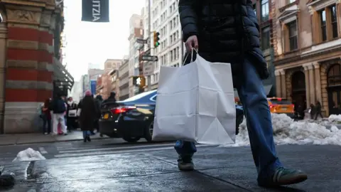 A shopper carries a bag in the SoHo neighborhood of New York, US, on Friday, Feb. 13, 2026. 