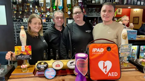 Four people standing behind a bar