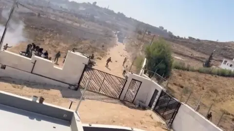 men and tear gas are seen outside ythe yard of a family home in the west bank