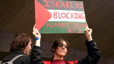PA Media Student drží znamení s textem „Izrael blokuje humanitární pomoc“, když se univerzitní studenti účastní rally na Sheffield University