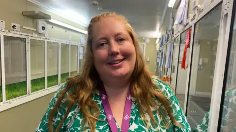 Charlie Munden, a woman with long hair, wearing a green leaf print shirt and a purple Cats Protection lanyard 