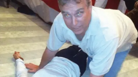 US DEPARTMENT OF JUSTICE Andrew Mountbatten-Windsor kneeling on all fours over an unidentified female body lying on the ground.  