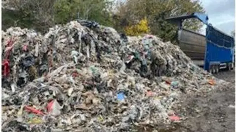 Staffordshire Police A large pile of waste material, with a blue HGV in the distance which appears to have dumped the rubbish in the foreground.