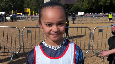 A young girl in running clothes outside the Mini London Marathon.