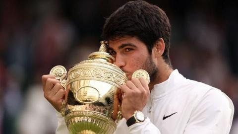 Carlos Alcaraz kisses the Wimbledon men's trophy following his victory against Novak Djokovic in last year's final