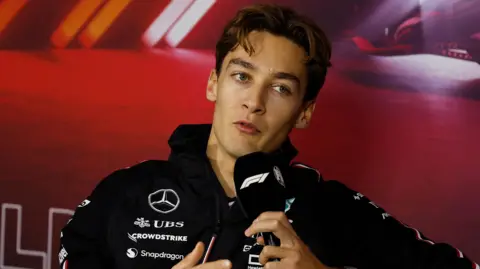 Mercedes driver George Russell speaking into a microphone with the F1 logo during the drivers' press conference for the Las Vegas Grand Prix