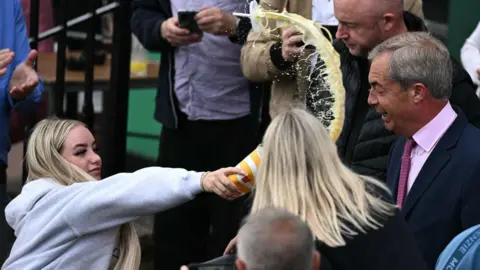 Getty Images A woman appears to throw a drink at Nigel Farage's face