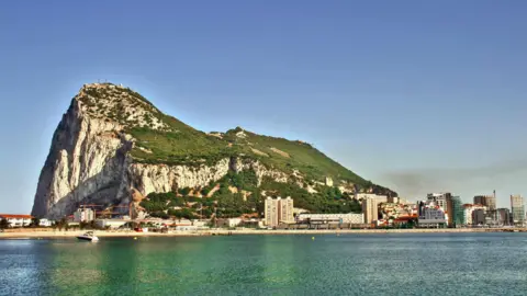 A wide shot of the rock of Gibraltar with the sea in the foreground.