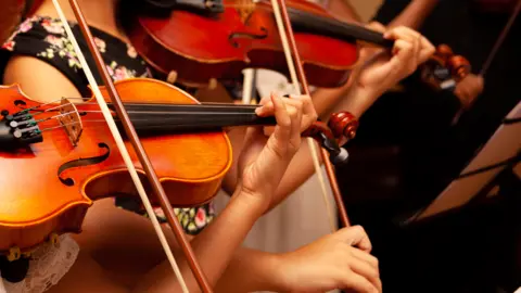Getty Images Children playing violins in a youth orchestra