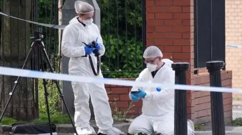 PA Forensic officers wearing white protective clothing and masks are picturing elements of the scene
