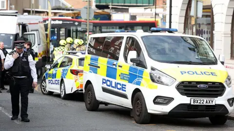 Getty Images A policeman standing in front of a police van and police car