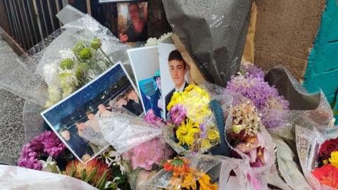 Pictures and flowers left on a street after death of teenager