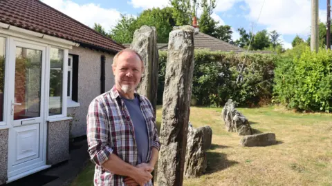 Andy Jonhson stood, over his shoulder is the famous split clovenstones