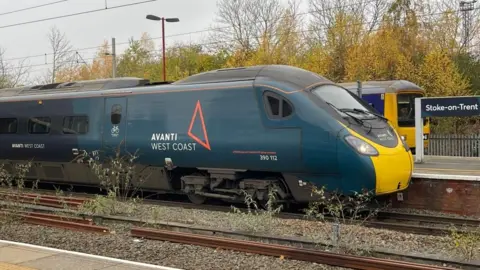 A dark green Avanti West Coast train pulling into Stoke-on-Trent station.