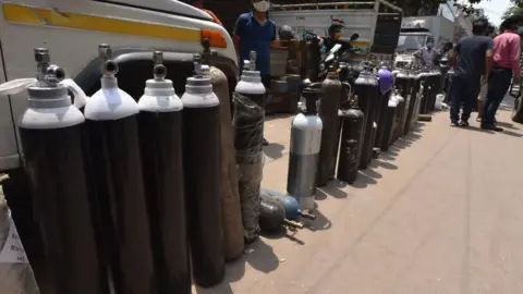 Getty Images Family members of Covid patients stand in long queue with empty oxygen cylinders outside the oxygen filling center to get their oxygen cylinders replenished at Bhogal Jangpura, on May 1, 2021 in New Delhi, India.