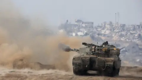 Reuters An Israeli tank fires towards Gaza from southern Israel (27 December 2023)