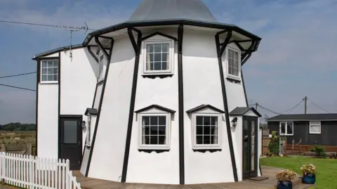 Historic England The Dutch Tutch, a converted helter-skelter, is on the waterside with a small patio surrounding it. 