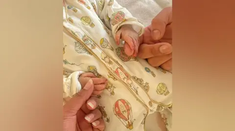 Family Mr and Mrs Binning's hands holding their baby's hands