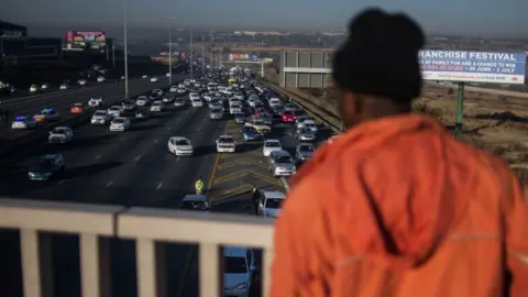 Getty Images A bystander looks on from a bridge as tr