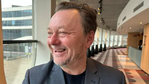 John Niven laughing and looking out of the window in the Birmingham Rep theatre bar