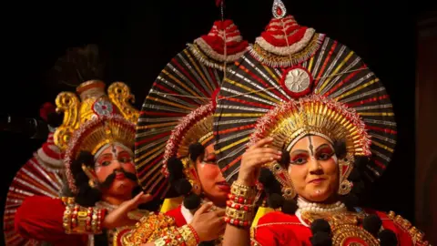Getty Images Women Yakshagana mākslinieki uzstājas kultūras izstādes laikā, lai atzīmētu Dasara svētkus 2024. gada 10. oktobrī Mysuru, Karnataka štatā, Indijā.