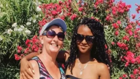 Lorraine with her granddaughter. They are hugging in a garden.