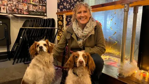 Suzie Broughton crouching next to her two rescue dogs.