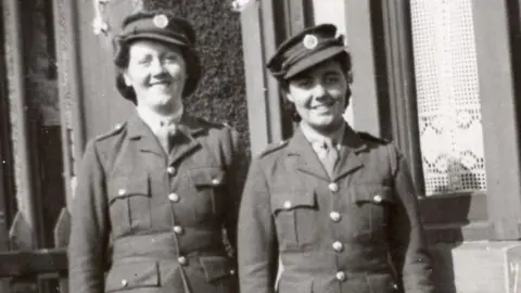 Christina Hartnell Christina Hartnell is standing outside her home in Hazelrigg, Newcastle with another woman. They are both in uniform.