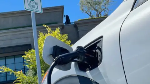 Getty Images An electric car charges at a parking lot in California.