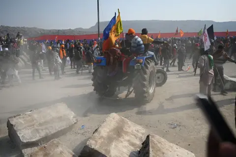 MONEY SHARMA/AFP Farmers on a tractor prepare to remove concrete barricades installed by police