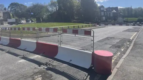 red and white traffic road barriers circling the top corner of South Street behind Sheffield train station.