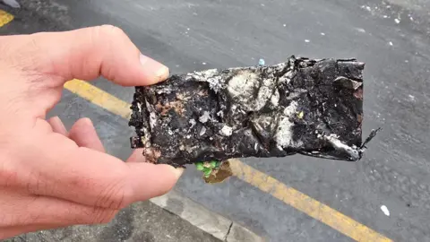 Nottingham City Council A hand holds the charred remains of a mobile phone which started a fire after being incorrectly discarded in a bin lorry. 