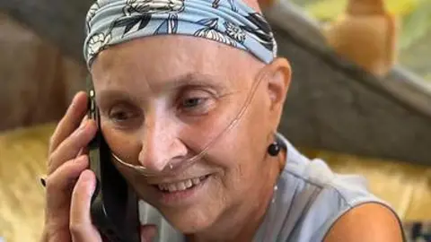 A woman wearing a blue headband holding a mobile phone up to her right ear