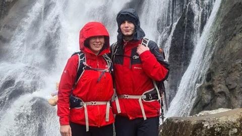 Sara Crosland with her son Daniel standing in front of a waterfall in walking gear