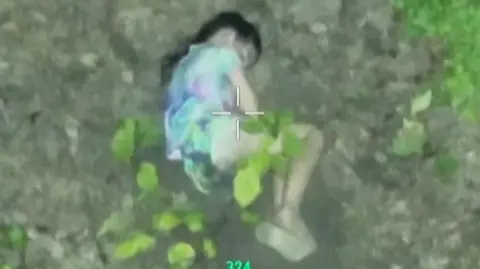 A girl is seen through a thermal drone lens, sleeping on the ground