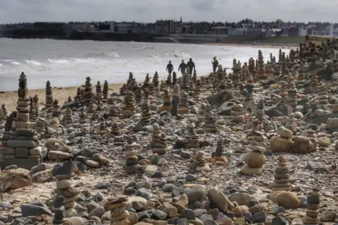 Owen Humphreys/PA Media Pebble stacks on beach