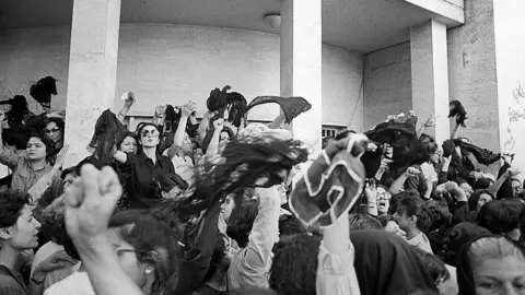 Getty Images A group of women protest against wearing the Islamic veil, while waving their veils in the air outside the office of the Prime Minister, Tehran, Iran, 6th July 1980