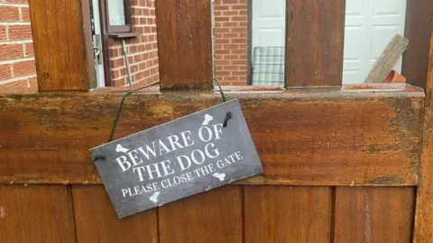 Liz O'Brien Sign reading 'Beware of the dog: Please close the gate' on Liz's gate post. 